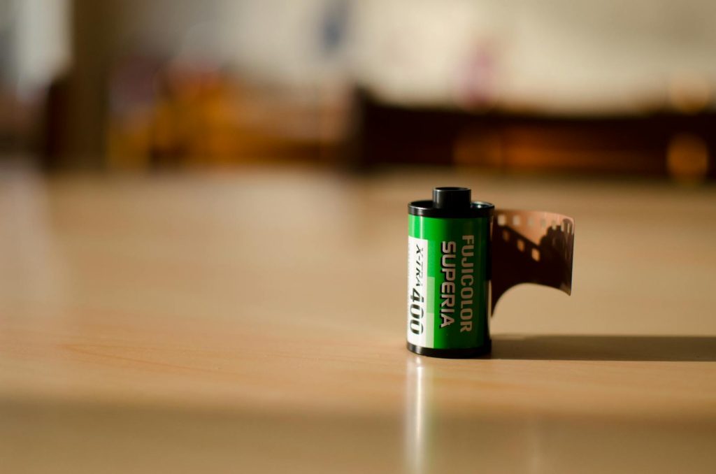 Contacta con PHOSKI Close-up of Fujicolor Superia film roll on a wooden table in natural light.